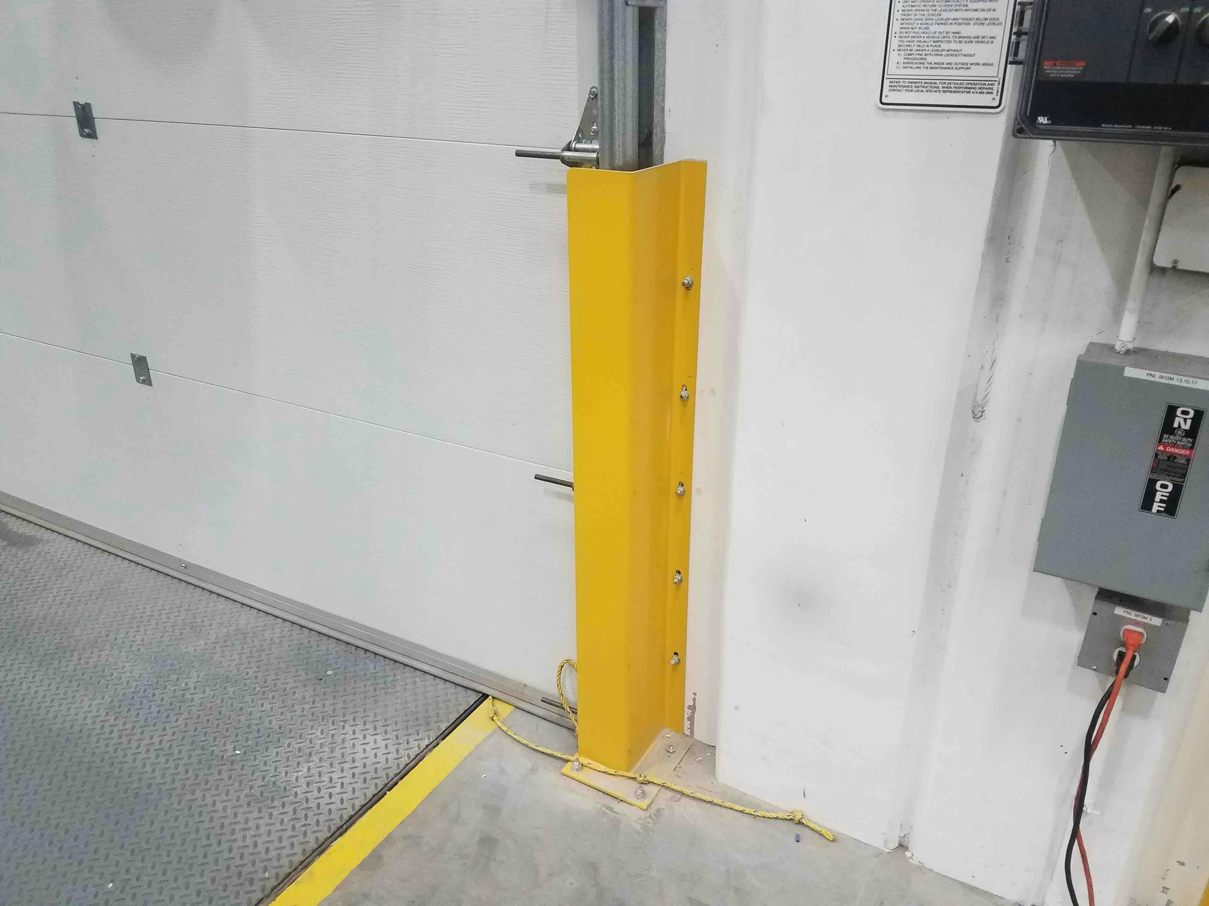 OSHA yellow Track Armor protecting vertical door rails in manufacturing warehouse